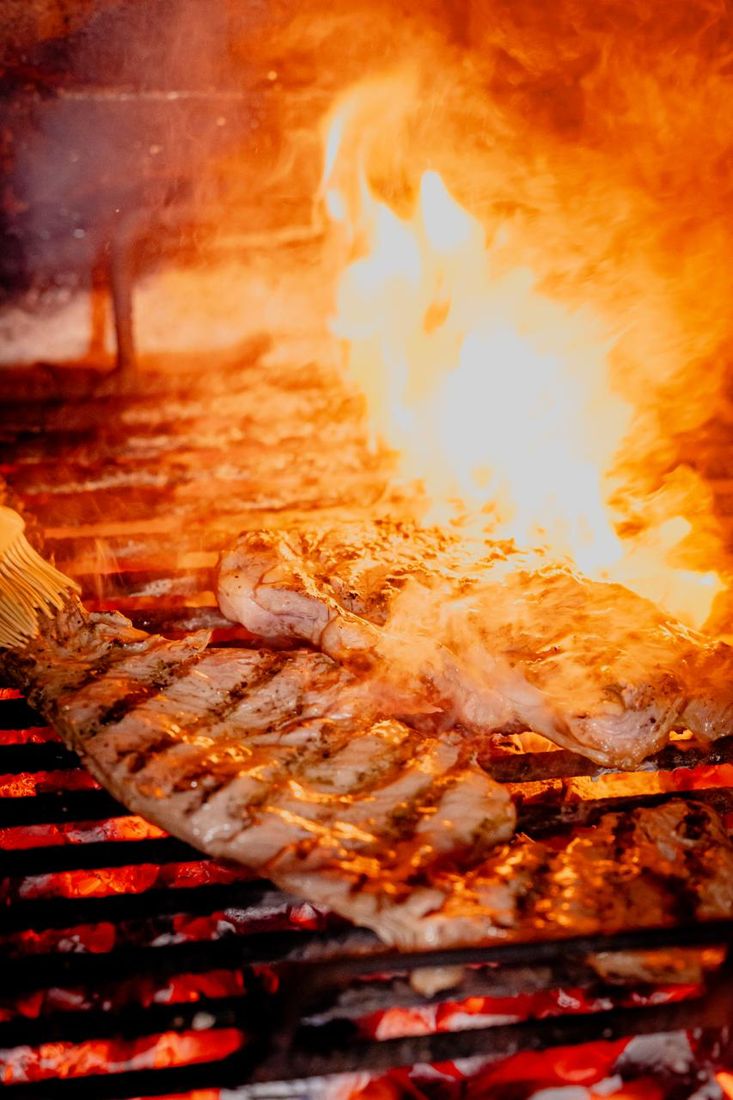 Carne asándose sobre la parrilla entre llamas