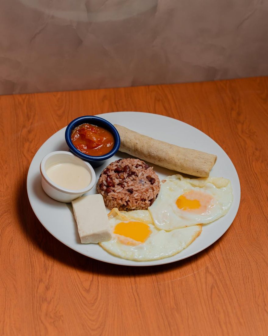 Desayuno típico con gallo pinto, huevos, queso, crema, tortilla y café