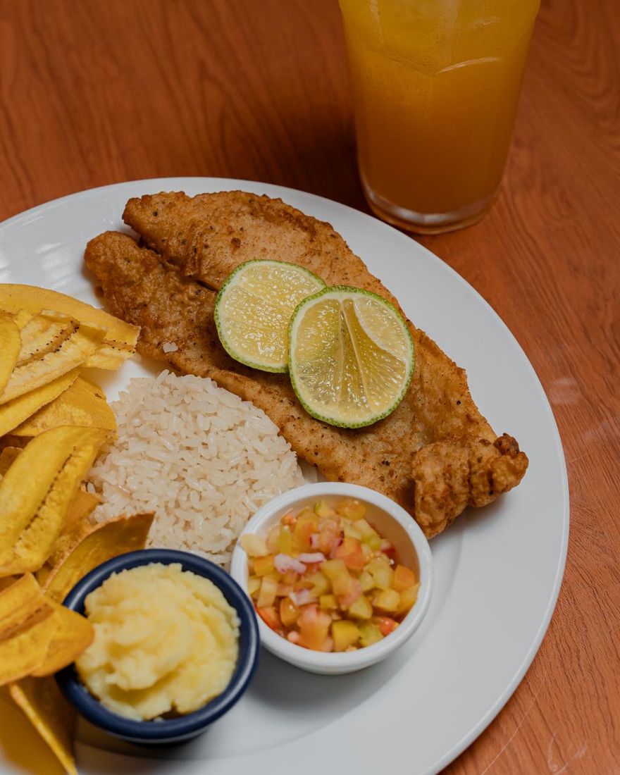 Filete de pescado empanizado con arroz, tajadas, puré, pico de gallo y limón